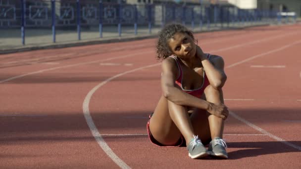Frustrado con los resultados deportista birracial solo sentado en medio de la pista — Vídeos de Stock