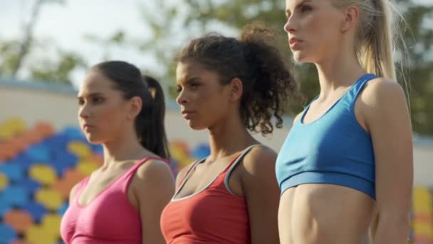 Three young sportswomen standing in one line, attentively listening to coach — Stock Video