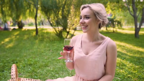 Lady elismeréssel megosztása Hírek barátjával, szürcsölgetve a bor park árnyékában — Stock videók