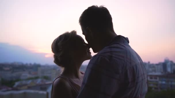 Пара захоплюється красивим рожевим заходом сонця, ніжно їх оточує, вид з даху — стокове відео