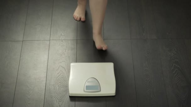 Gesunde Ernährung, pummeliges Weibchen, das auf die Waage tritt, um das Gewicht zu kontrollieren, Körperkontrolle — Stockvideo