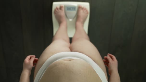 Толстая женщина на весах со словом диета на экране, вопрос, если сесть на диету, гнев — стоковое видео