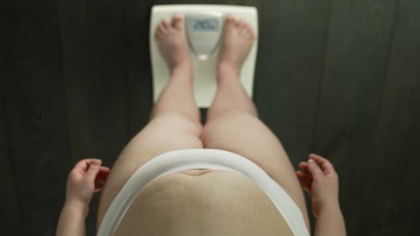 Obese woman standing on bathroom scales, checking weight, anxious, top-view — Stock Video