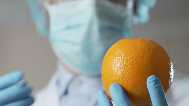 Investigador de laboratorio inyectando sustancia en naranja, trabajando en cosméticos anticelulíticos — Vídeos de Stock