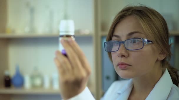 Médica estudando ingredientes de medicamentos, olhando para o rótulo do recipiente da pílula — Vídeo de Stock