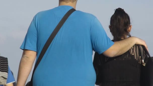 Tinggi kelebihan berat badan laki-laki berjalan dengan lengannya di bahu perempuan, gerakan lambat — Stok Video