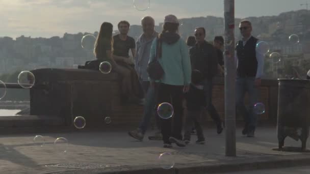 Neapol, Itálie - cca červenec 2014: Lidé ve městě. Lidí, kteří jdou po nábřeží město obklopené mýdlové bubliny plovoucí ve vzduchu — Stock video