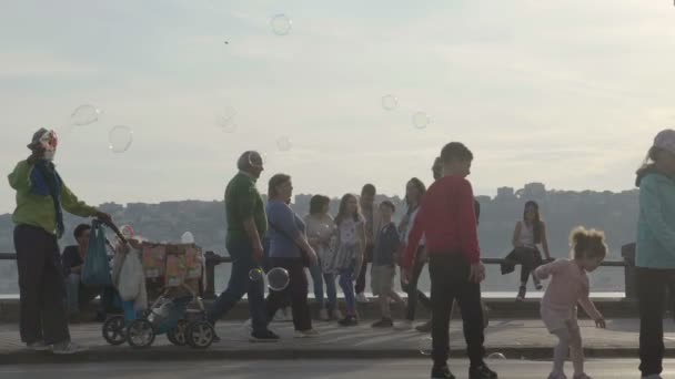 НАПЛЕС, ИТАЛИЯ - CIRCA JULY 2014: Люди в городе. Продавец посылает мыльные пузыри людям, проходящим мимо, дети пытаются поймать их — стоковое видео