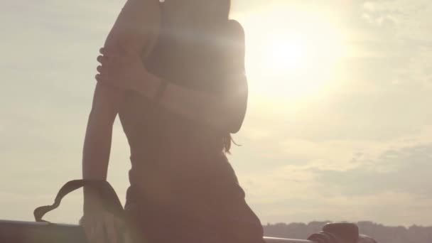 Meisje leunend op de leuning in straat tegen zonovergoten hemel, arm aanraken als koud — Stockvideo