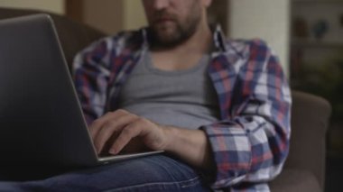 Laptop, erteleme ve duyarsızlık lazily yazarak kanepede yatan yorgun adam