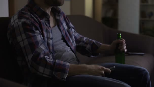 Beschwipster Mann gestikuliert mit Fernbedienung vor dem Fernseher, Bier in der Hand, wütend — Stockvideo