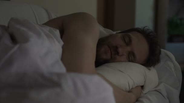 Раздраженный человек бросает и поворачивается в постели не в состоянии заснуть, шумные соседи — стоковое видео