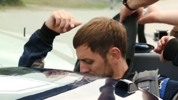 Hombre sentado en coche deportivo, miembro de la tripulación abrochando cinturones de seguridad, competición de carreras — Vídeos de Stock