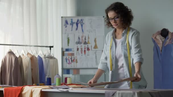 Diseñador sonriente mirando los patrones y planeando su colocación en la tela — Vídeos de Stock