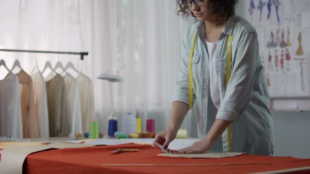 Tailor circling sketch of pattern and beginning to cut workpiece from fabric — Stock Video