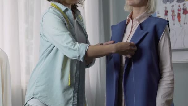 Mulher costureira criativa encaixe detalhes casaco na senhora do cliente e cabeça acenando — Vídeo de Stock