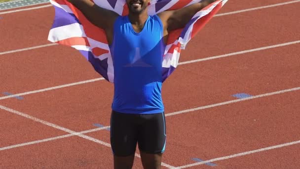 Gespierde lid van Britse sportteam triomfantelijk bedrijf vlag boven zijn hoofd — Stockvideo