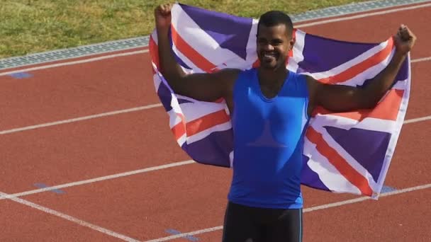 Glücklicher Athlet hält Fahne seines Landes in den Händen, Großbritannien ist stolz auf Sieger — Stockvideo