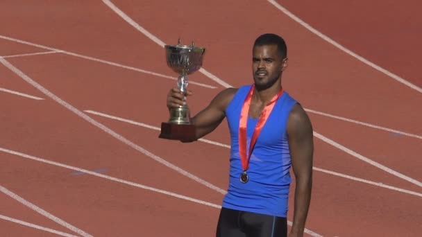 Spansktalande sportsman med guldmedalj på bröstet holding cup, förverkliga sin seger — Stockvideo