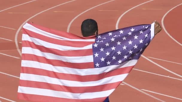 Спортсмен с флагом США демонстрирует свою победу на международных соревнованиях — стоковое видео