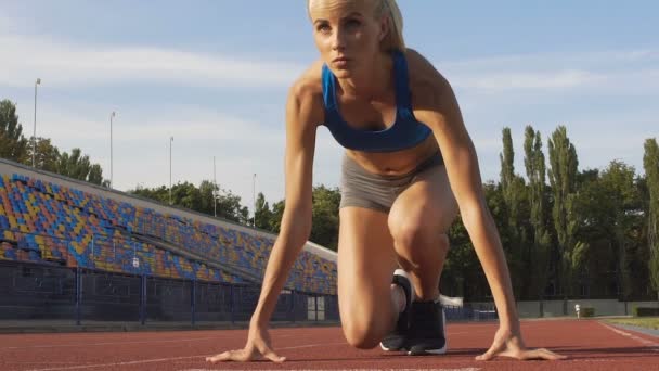 Vista frontal de la motivada atleta femenina saliendo de la línea de salida en el estadio, deporte — Vídeos de Stock