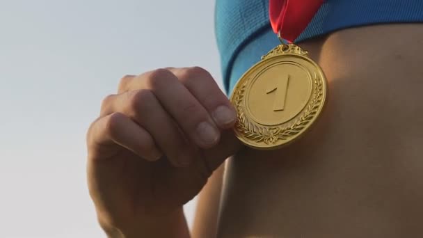 Happy sportswoman rejoicing her victory at competition and touching gold medal — Stock Video