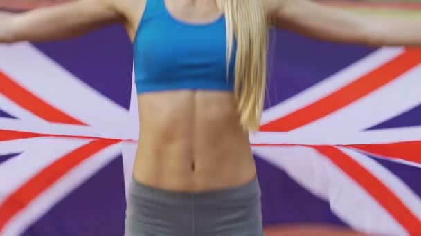 Slanke Sportvrouw springen en houden van de Britse vlag, viert haar overwinning in wedstrijd — Stockvideo