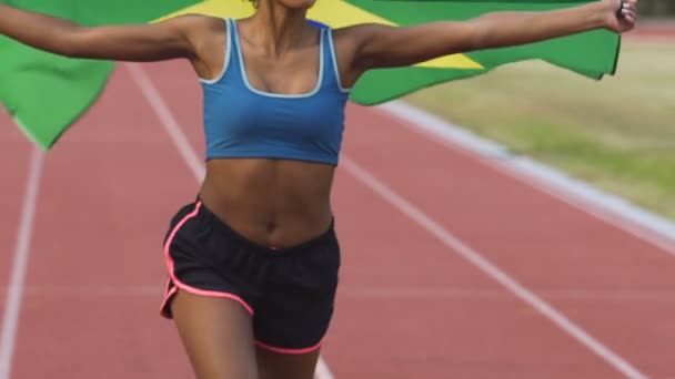 Vrouwelijke atleet gemengd ras waarop stadion met de vlag van Brazilië, patriottisme — Stockvideo