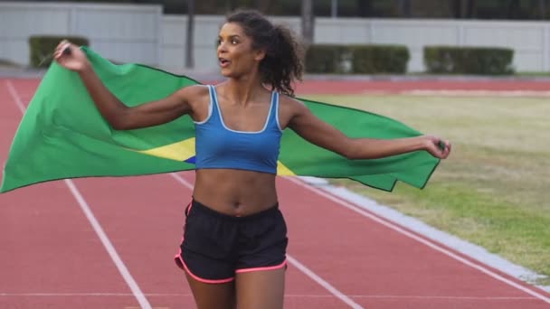 En vakker sportskvinne med Brasils flagg som stråler glede og feirer seier – stockvideo