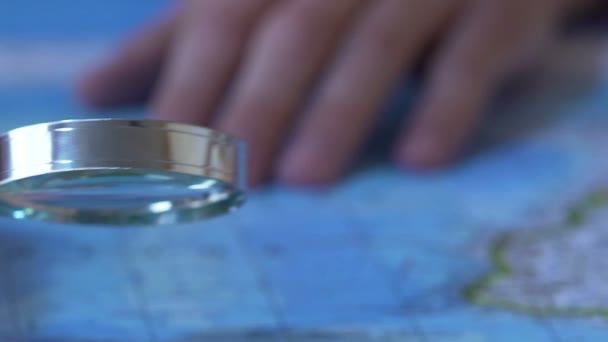 Homme regardant la carte du monde à travers la loupe, choisir un endroit à visiter — Video