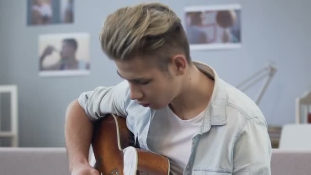 Талантливый мальчик играет на гитаре дома, подбирает мелодии, музыкальное хобби, развлечения — стоковое видео