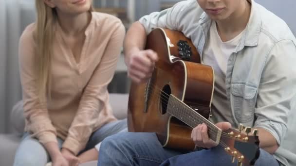 Aranyos tizenéves férfi gitározni a főiskola része, a lány hallgat, az első szerelem — Stock videók