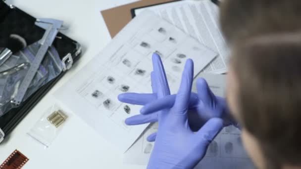 Detektiv med examen handskar, kontrollera kulor från brottsplatsen med förstoringsglas — Stockvideo