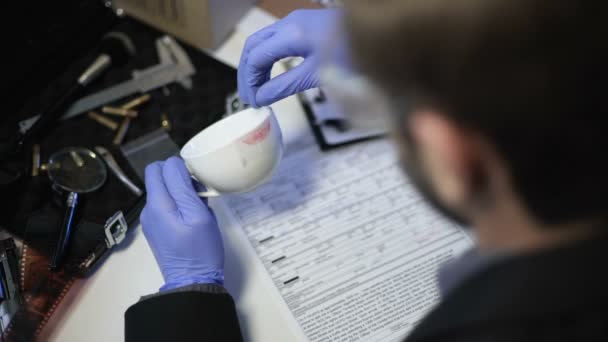 Detective hijs lippenstift print op beker, verzamelen van biologische gegevens, achteraanzicht — Stockvideo