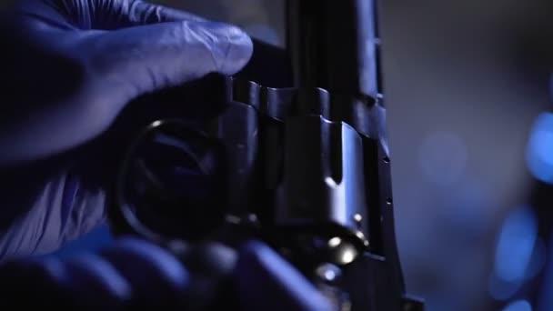 Криминалист проводит судебную экспертизу револьвера, проверяет бочку крупным планом — стоковое видео