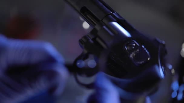 Esperto forense che guarda il numero di serie sul revolver, usando una lente d'ingrandimento — Video Stock