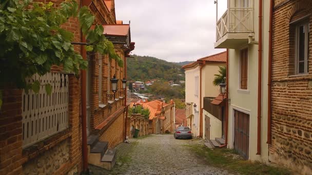 Coches y ciudadanos en calles estrechas y empedradas con casas acogedoras en el pueblo georgiano — Vídeo de stock