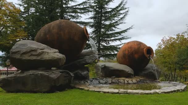Креативный кувшин с когтями, окруженный огромными камнями, расположенный в зеленом парке, искусство — стоковое видео