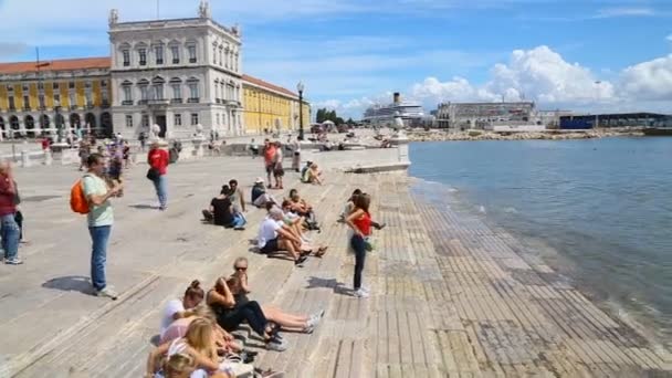 LISBOA, PORTUGAL - CIRCA AGOSTO 2014: Passeios turísticos na cidade. Turistas relaxados sentados à beira-mar, desfrutando de bela vista e brisa leve — Vídeo de Stock