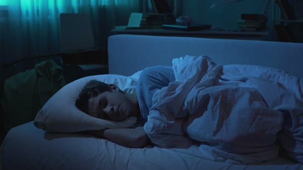 Заботливая мать покрывает спящего сына одеялом в ночное время, семейная любовь — стоковое видео