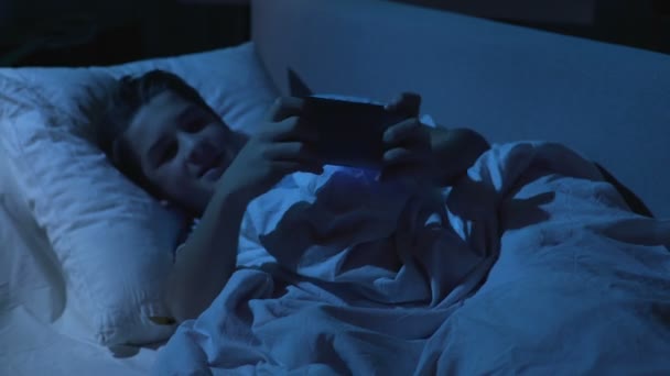 Подросток прячет телефон под подушкой и притворяется спящим, семейный контроль — стоковое видео