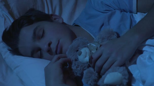 Милий підліток чоловік спить у ліжку з іграшкою плюшевого ведмедя, дитинство, солодкі сни — стокове відео