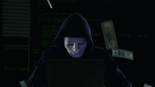 Hacker in maschera che lavora su laptop, banconote da un dollaro che cadono, riciclaggio di denaro — Video Stock