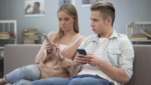 Novio adolescente y novia de compras en línea en los teléfonos inteligentes, adicción — Vídeos de Stock