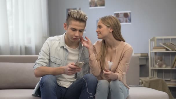 Flicka med hörlurar av, blygt antyda att killen för nästa steg i relation — Stockvideo