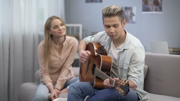Boy in love playing guitar to girlfriend conquering her heart, romantic date — Stock Video
