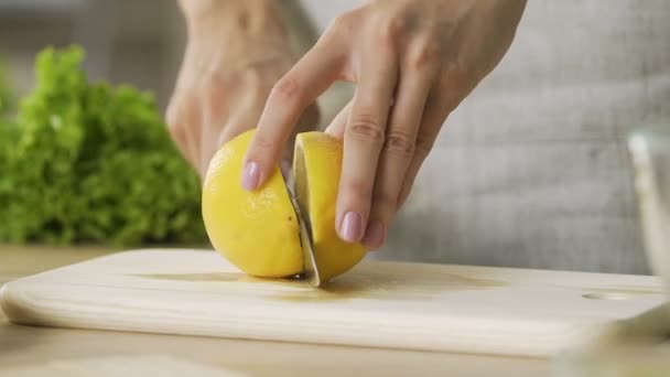 Primer plano señora manos corte limones amarillos, hacer limonada fresca, cocinar — Vídeo de stock