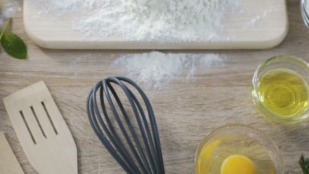 Домохозяйка разбивает яйцо в муку на кухонной доске, делая тесто по рецепту пирога — стоковое видео