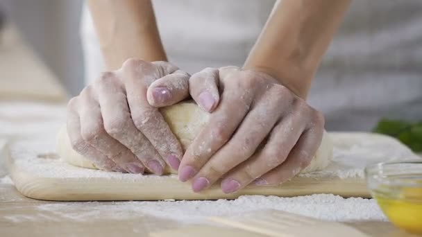 Nærme, kvinnelige hender som kneler fersk deig på kjøkkenet, baking – stockvideo