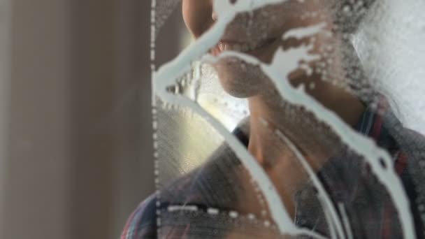 Улыбающаяся женщина-чистильщица стирает стеклянные перегородки в офисе, протирая пену и пятна — стоковое видео